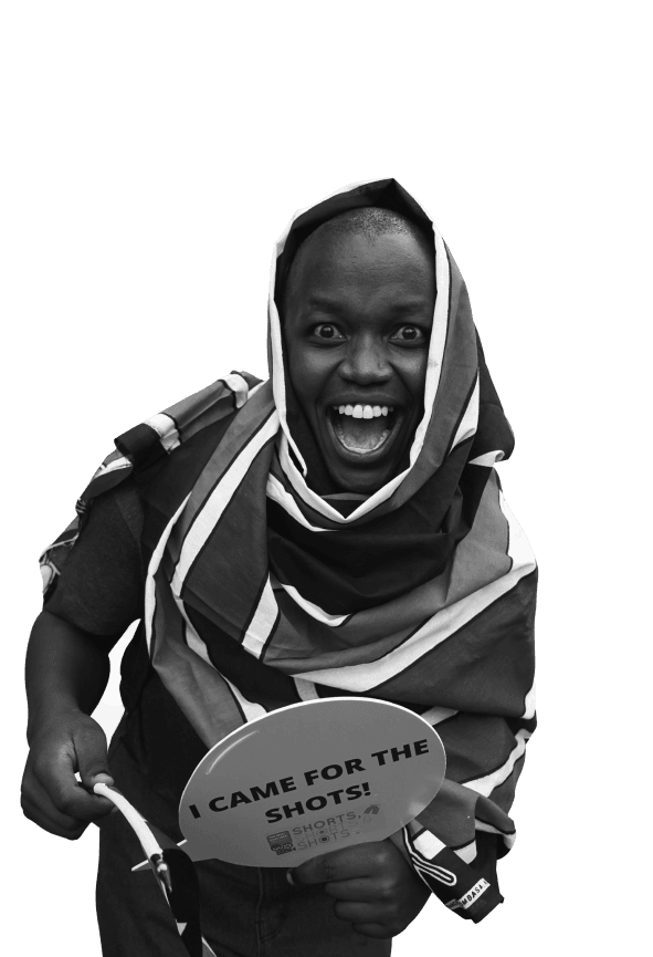 Filmmaker wrapped in a Kenyan flag holding a sign reading I came for the shots